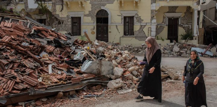 Unas mujeres caminan junto a las ruinas de unos edificios en Hatay, una de las ciudades más afectadas por los devastadores terremotos que asolaron el sur de Turquía a principios de año.