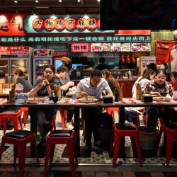 Varias personas cenan en un restaurante de un centro comercial de Pekín, China. | Foto:JADE GAO / AFP