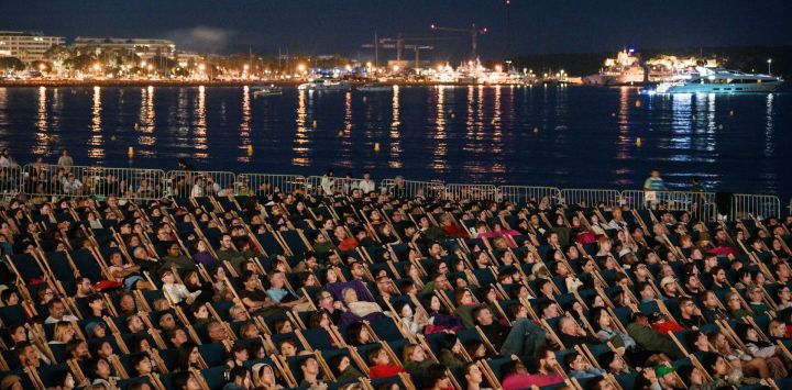 Espectadores ven la película "The Way of the Dragon" en el "Cinema de la plage" durante la 76ª edición del Festival de Cine de Cannes en Cannes, sur de Francia.