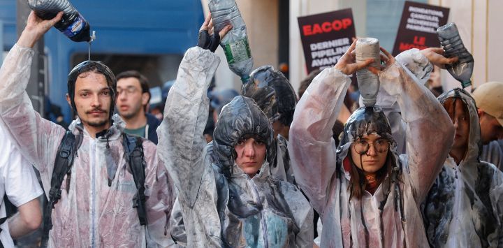 Manifestantes por el clima vierten aceite sobre ellos mientras se producen refriegas entre la policía y los manifestantes con el uso de gases lacrimógenos durante una manifestación a las afueras de la sede de la Asamblea General Anual de TotalEnergies en París.