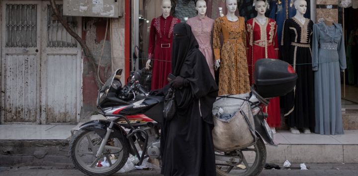 Una mujer siria con niqab se apoya en una motocicleta en el barrio de Kocavezir de Adana, en el sur de Turquía, que acoge a un gran número de refugiados sirios que huyeron de la guerra civil.