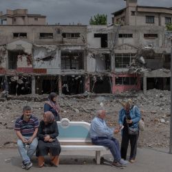 Varias personas esperan en una parada de autobús frente a un edificio destruido durante la segunda vuelta de las elecciones presidenciales en la ciudad de Kahramanmaras, Turquía, afectada por un terremoto. | Foto:CAN EROK / AFP