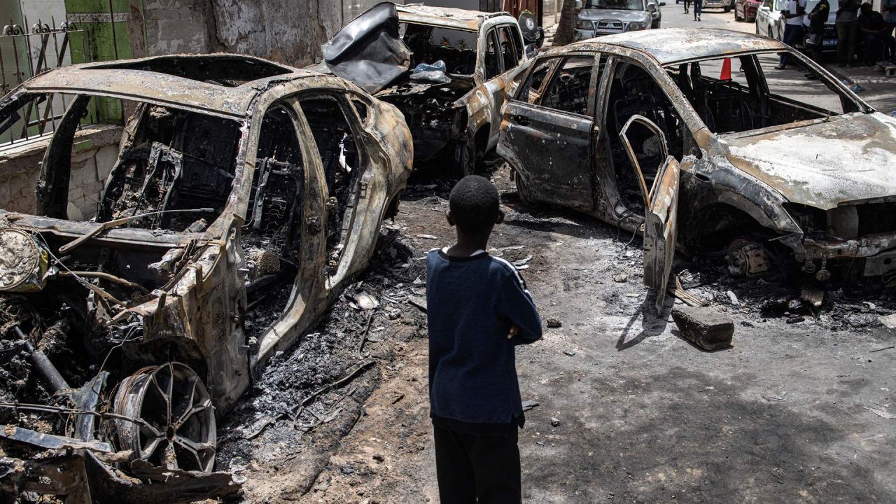 Un niño observa los coches quemados de Matar Ba, jefe de gabinete del presidente de Senegal, Macky Sall, en Dakar, Senegal. Las protestas estallaron en los alrededores de Dakar por la detención del líder de la oposición senegalesa Ousmane Sonko antes del veredicto final en su proceso por violación. | Foto:JOHN WESSELS / AFP