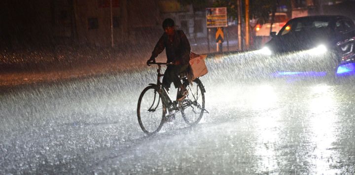 Los transeúntes se abren paso por una calle durante un fuerte aguacero en Jalandhar, India.