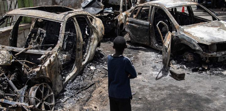 Un niño observa los coches quemados de Matar Ba, jefe de gabinete del presidente de Senegal, Macky Sall, en Dakar, Senegal. Las protestas estallaron en los alrededores de Dakar por la detención del líder de la oposición senegalesa Ousmane Sonko antes del veredicto final en su proceso por violación.