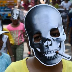 Un escolar con una mascarilla de una calavera con un cigarrillo participa en una concentración de concienciación contra el consumo de tabaco en el "Día Mundial sin Tabaco" en Calcuta. | Foto:DIBYANGSHU SARKAR / AFP