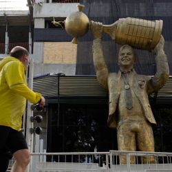 Un corredor mira una escultura del ex entrenador de River Plate Marcelo Gallardo levantando el trofeo de la Copa Libertadores fuera del estadio Monumental en Buenos Aires. | Foto:JUAN MABROMATA / AFP