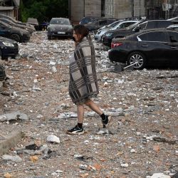 Un residente local camina entre coches dañados al salir de un edificio residencial de varias plantas, parcialmente destruido tras los ataques nocturnos con drones en Kiev, Ucrania. | Foto:SERGEI SUPINSKY / AFP