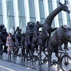 Una persona se sienta sobre una escultura de bronce de los artistas Gillie y Marc titulada "They were on a wild ride to a safer place with Rabbitwoman and Dogman", que forma parte de la exposición "A Wild Life For Wildlife" en el Oculus Center de Nueva York. | Foto:TIMOTHY A. CLARY / AFP