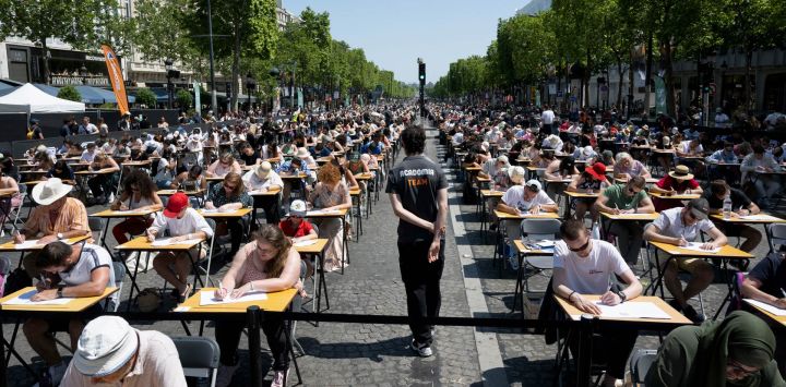 Los participantes intentan batir el récord del "Dictado más grande del mundo" en la prestigiosa avenida de los Campos Elíseos, transformada en un aula gigante, en París.