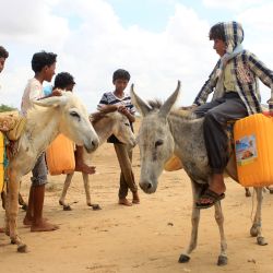 Niños yemeníes montan en burros para transportar contenedores de agua en un campamento para desplazados en el distrito de Abs, en la provincia noroccidental de Hajjah. | Foto:ESSA AHMED / AFP