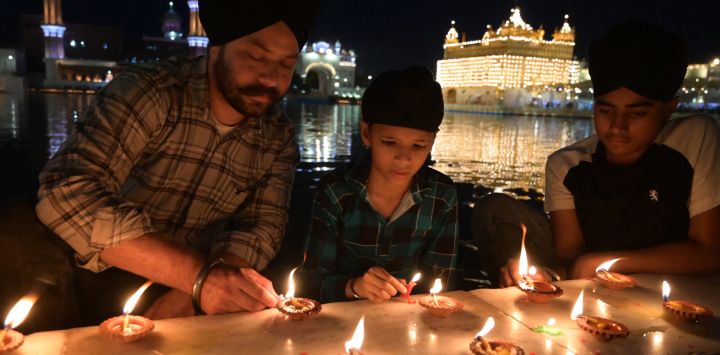 Devotos sijs encienden lámparas de aceite de tierra mientras rinden homenaje con motivo del aniversario del nacimiento de Guru Hargobind Singh en el Templo Dorado de Amritsar, India.