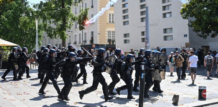 Gendarmes con equipo antidisturbios corren mientras se lanza una bengala durante los enfrentamientos con los manifestantes en el 14º día de acción después de que el gobierno impulsara una reforma de las pensiones a través del parlamento sin votación, utilizando el artículo 49.3 de la constitución, en Nantes, oeste de Francia.