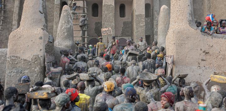 Varias personas transportan cubos de barro para revocar la Gran Mezquita de Djenne, en el centro de Malí. Miles de habitantes de Djenne se reúnen cada año para revocar los muros de la Gran Mezquita de Djenne, construida con barro desde 1907.