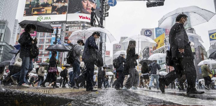 Varias personas utilizan sus paraguas para resguardarse de la lluvia mientras caminan por el distrito de Shibuya, en Tokio, Japón.