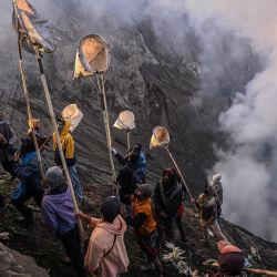 Los aldeanos utilizan redes para recoger las ofrendas lanzadas por los miembros del grupo subétnico Tengger en el cráter del volcán activo del monte Bromo como parte del festival Yadnya Kasada en Probolinggo, provincia de Java Oriental, Indonesia. | Foto:JUNI KRISWANTO / AFP