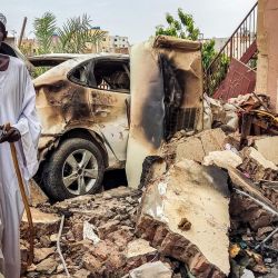 Un hombre inspecciona los daños mientras camina entre los escombros junto a un coche destruido en el exterior de una casa alcanzada por un proyectil de artillería en el distrito de Azhari, en el sur de Jartum, Estados Unidos y Arabia Saudí volvieron a impulsar las conversaciones para una tregua entre los generales sudaneses enfrentados. | Foto:AFP