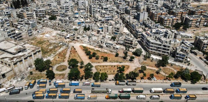 Esta vista aérea muestra camiones de grano que transportan trigo cosechados en las afueras de la ciudad siria de Idlib, controlada por los rebeldes en el noroeste del país, a un silo en el centro de la ciudad.
