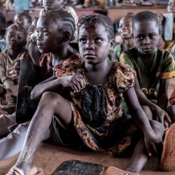 Alumnos de primer grado aprenden sentados en el suelo debido a la insuficiencia de mesas y sillas en el interior del mayor campo de desplazados de la República Centroafricana, en Bria. | Foto:BARBARA DEBOUT / AFP