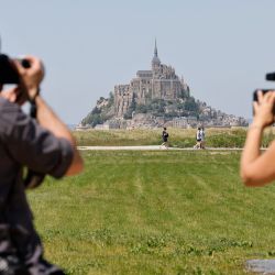 Periodistas trabajan frente al Mont-Saint-Michel francés durante la visita de dos días del presidente francés en Normandía, en Le Mont-Saint-Michel, noroeste de Francia. | Foto:Ludovic Marin / POOL / AFP
