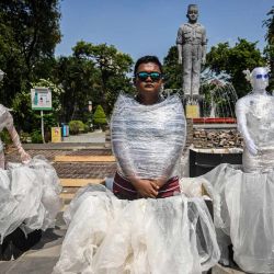 Una activista medioambiental vestida de plástico junto a maniquíes vestidos con residuos plásticos participa en una campaña contra el cambio climático en Surabaya, Indonesia. | Foto:JUNI KRISWANTO / AFP
