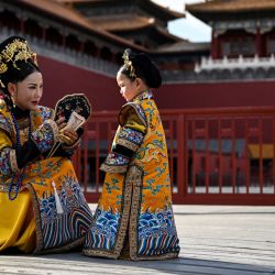 Una mujer y una niña vestidas con un traje tradicional chino charlan junto a la Ciudad Prohibida durante una sesión de fotos con un fotógrafo local en Pekín. | Foto:HECTOR RETAMAL / AFP