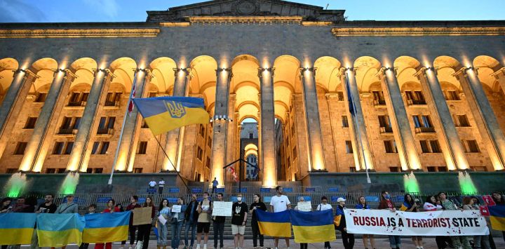 Activistas con banderas ucranianas celebran una concentración contra Rusia tras la destrucción de la presa de Kajovka, en Ucrania, controlada por Rusia, frente al Parlamento georgiano en Tiflis.