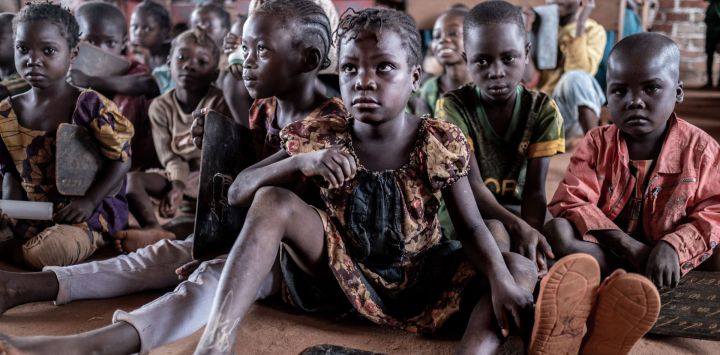 Alumnos de primer grado aprenden sentados en el suelo debido a la insuficiencia de mesas y sillas en el interior del mayor campo de desplazados de la República Centroafricana, en Bria.