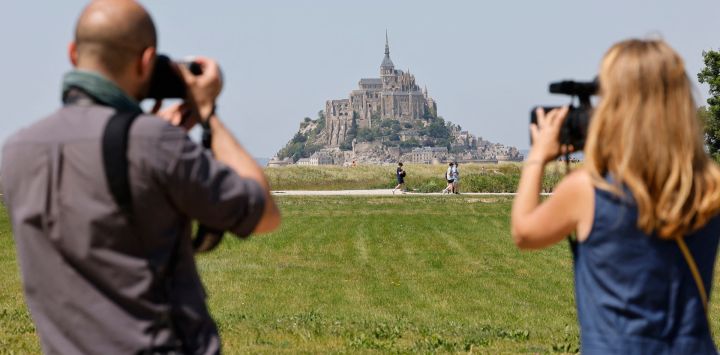 Periodistas trabajan frente al Mont-Saint-Michel francés durante la visita de dos días del presidente francés en Normandía, en Le Mont-Saint-Michel, noroeste de Francia.