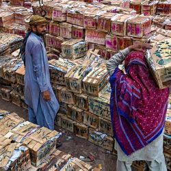 Un trabajador transporta una caja de mangos en un mercado de Lahore, Pakistán. | Foto:ARIF ALI / AFP
