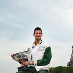 El serbio Novak Djokovic posa con el Trofeo de los Mosqueteros, mientras se ve la Torre Eiffel al fondo, durante un photocall tras ganar el torneo de tenis Roland-Garros French Open, en París. | Foto:EMMANUEL DUNAND / AFP