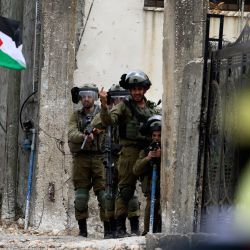 Un manifestante con una bandera nacional palestina camina junto a las tropas israelíes, durante los enfrentamientos con ellos después de una protesta contra la expropiación de tierras palestinas por Israel en la Cisjordania ocupada, en el pueblo de Kfar Qaddum, cerca del asentamiento judío de Kedumim. | Foto:JAAFAR ASHTIYEH / AFP