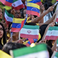 Mujeres jóvenes ondean banderas nacionales de Venezuela e Irán durante la llegada del presidente iraní Ebrahim Raisi al Palacio Presidencial de Miraflores, en Caracas. | Foto:YURI CORTEZ / AFP