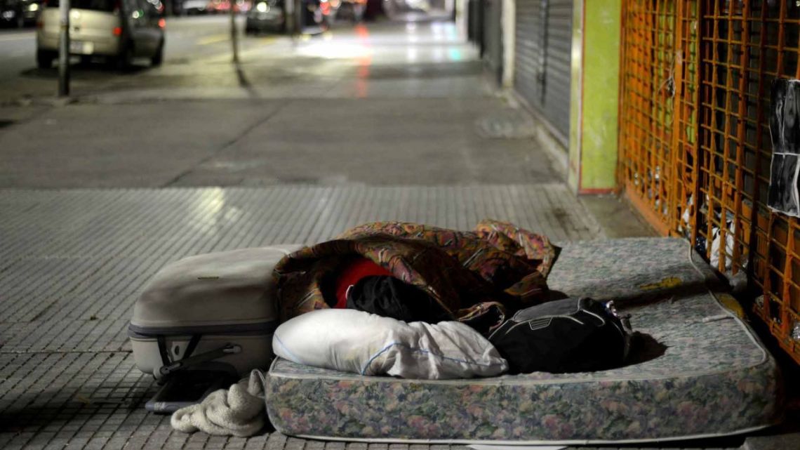 A homeless person sleeps on the streets of Buenos Aires at night.