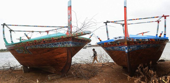 Un policía camina junto a barcos de pesca varados en una playa cerrada en Karachi, mientras el ciclón Biparjoy se abre paso a través del mar Arábigo hacia las costas de Pakistán.