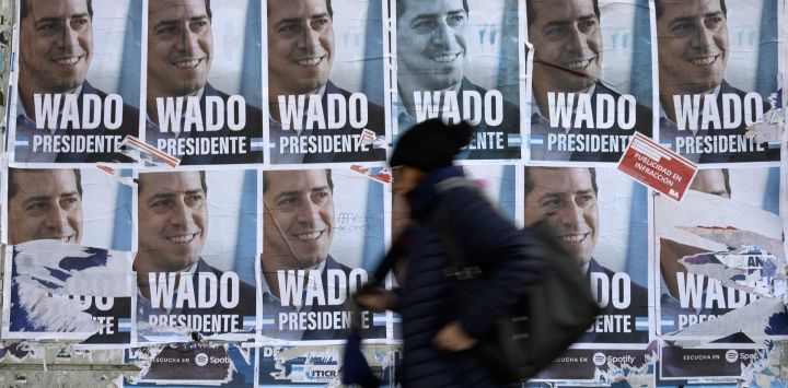 Una mujer camina junto a pancartas con el retrato del ministro del Interior de Argentina, Eduardo De Pedro, más conocido como Wado, en las que se lee "Wado Presidente", en Buenos Aires, antes de las elecciones primarias que se celebrarán el 13 de agosto.