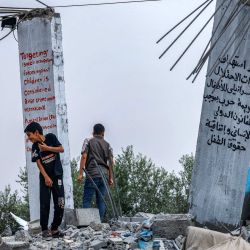 Niños palestinos posan junto a murales durante una exposición de arte mixto titulada "La ocupación mata a la infancia" que tiene lugar entre los escombros de las casas destruidas por los ataques aéreos israelíes durante el conflicto de mayo de 2023 en Deir al-Balah, en el centro de la Franja de Gaza. | Foto:MOHAMMED ABED / AFP