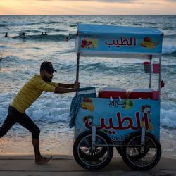 Un vendedor de helados busca clientes en una playa de la ciudad de Gaza cerca del atardecer. | Foto:Jewel Samad / AFP