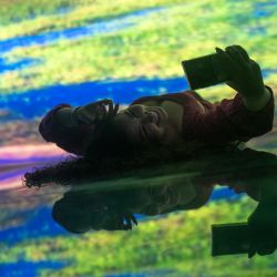 Una mujer se toma un selfie mientras visita la exposición "Océano de Espejos", que es un conjunto de salas con proyecciones y espejos que muestran a los visitantes en la multiplicidad y el entorno natural, en el Acuario Marino de Río de Janeiro, Brasil. | Foto:MAURO PIMENTEL / AFP