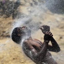 Un hombre se refresca por una fuga de agua en el caluroso clima de Karachi, Pakistán. | Foto:ASIF HASSAN / AFP