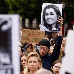 Un manifestante sostiene una imagen que muestra a la difunta Dorota, que murió en su quinto mes de embarazo, frente al monumento a Copérnico, en el centro de Varsovia, mientras la gente sale a la calle para protestar bajo el título "Ni una más" y "Dejad de matarnos" contra la ley del aborto tras la muerte de la mujer embarazada. | Foto:WOJTEK RADWANSKI / AFP