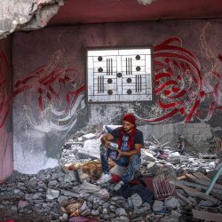 El artista palestino Ayman Alhossary finaliza los dibujos de caligrafía árabe sobre los restos de una casa destruida por los ataques aéreos israelíes durante el conflicto de mayo de 2023, en Beit Lahia, en el norte de la Franja de Gaza. | Foto:MOHAMMED ABED / AFP