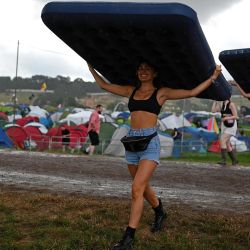 Los asistentes al festival llevan colchones hinchables bajo la lluvia durante el primer día del festival de Glastonbury en el pueblo de Pilton, en Somerset, suroeste de Inglaterra. | Foto:OLI SCARFF / AFP