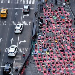 Un grupo de personas participa en el evento anual de yoga en Times Square, Nueva York. Durante los últimos veinte años, los organizadores han celebrado el evento de yoga en el día más largo del año, en una de las intersecciones más concurridas del mundo, para promover la paz y la calma. | Foto:TIMOTHY A. CLARY / AFP