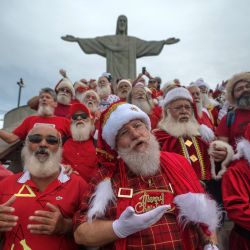 Un grupo de Papá Noel cantan durante una visita a la estatua del Cristo Redentor en Río de Janeiro, Brasil, después de asistir a la Convención Nacional de Papá Noel organizada por la Escuela de Papá Noel de Brasil. | Foto:MAURO PIMENTEL / AFP