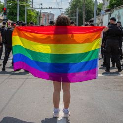 Un juerguista sostiene una bandera arco iris frente a un cordón de fuerzas de seguridad durante la Marcha del Orgullo en el centro de Chisinau. Cientos de juerguistas, fuertemente custodiados por fuerzas policiales y gendarmes, participaron en la marcha de la 22ª edición del festival LGBTQ+ de Moldavia. | Foto:ELENA COVALENCO / AFP