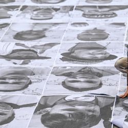 Una mujer coloca retratos de refugiados y retornados en el suelo durante una actividad realizada por el proyecto artístico Inside Out en el marco del Día Mundial del Refugiado en Bogotá, Colombia. | Foto:JUAN BARRETO / AFP