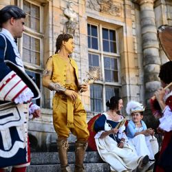 Personas ataviadas con trajes del siglo XVII participan en "La grande journee des costumés", un acontecimiento histórico que reúne a cientos de personas en el castillo de Vaux-le-Vicomte (al fondo), en Maincy, a unos 50 km al sureste de París. | Foto:CHRISTOPHE ARCHAMBAULT / AFP