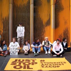 Activistas climáticos de Just Stop Oil realizan una sentada tras lanzar pintura naranja contra la sede británica de TotalEnergies en el distrito londinense de Canary Wharf para protestar contra la construcción del oleoducto de África Oriental (EACOP, por sus siglas en inglés). | Foto:HENRY NICHOLLS / AFP