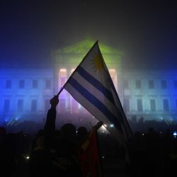 Una bandera uruguaya ondea frente al Palacio Legislativo durante una vigilia en conmemoración del 50 aniversario del inicio de la dictadura uruguaya (1973-1985) en Montevideo. | Foto:PABLO PORCIUNCULA / AFP